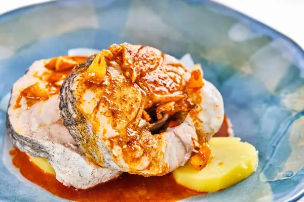 Merluza a la gallega con patatas y salsa de pimentón, un plato tradicional gallego lleno de sabor.